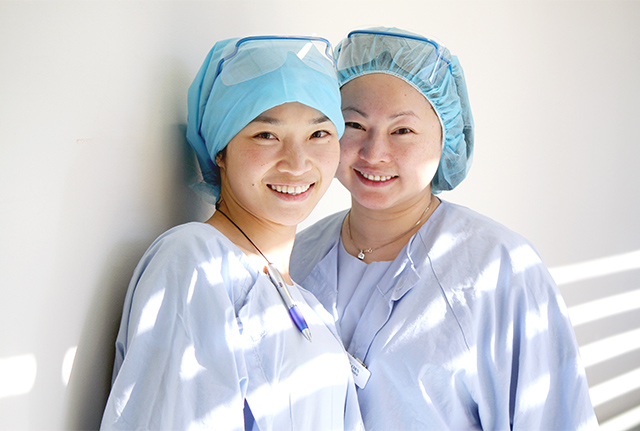 Two smiling nurses in surgical attire