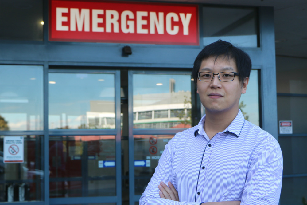 Michael Zhang standing in front of Emergency sign