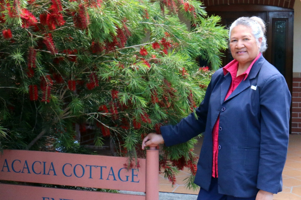 Taiana Fangupo standing next to Acacia Cottage sign