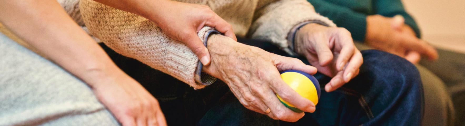 Close up of holding hands a younger person and an older person holding a ball.