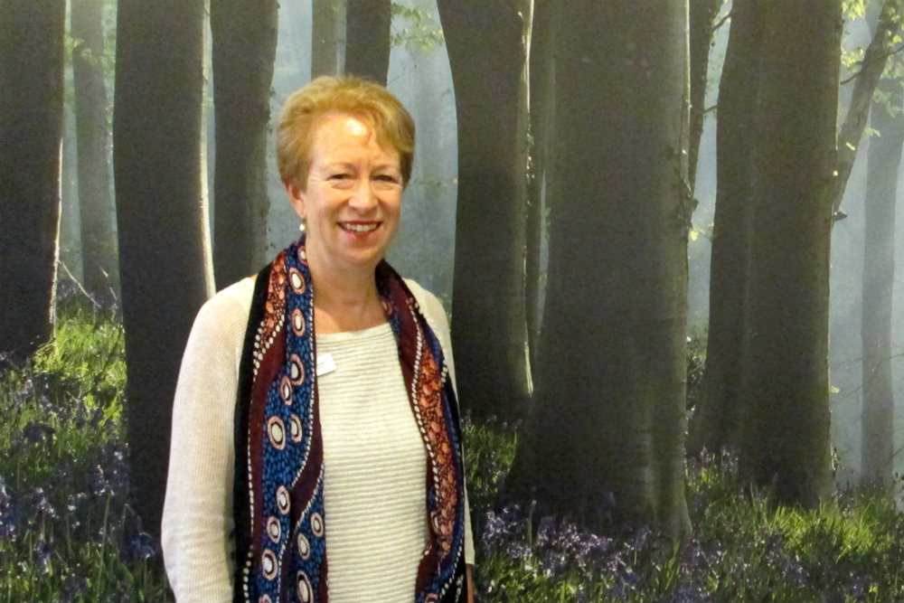 Anne Lainchbury standing in front of forest mural